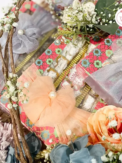 A detail shot of the mithai boxes, showing the delicate pearl and floral ribbon work.