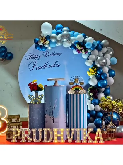 A third birthday party with a blue and silver circular backdrop and balloon garland.