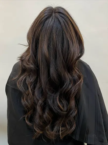 The 'after' shot of a beautiful colour correction and styling. We transformed uneven, brassy tones into these gorgeous, seamless chocolate brown waves that look healthy and vibrant.