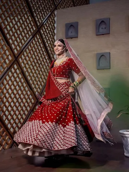 A joyful bridal portrait showing the bride twirling in her stunning red lehenga. Her movement and smile capture the excitement of the wedding day.