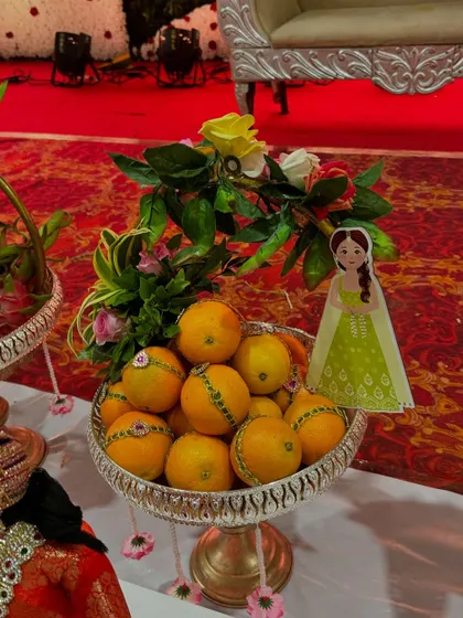 A fruit platter of oranges decorated with a small cutout of a girl in a green dress.