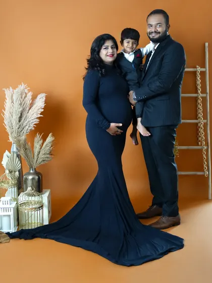A formal family maternity portrait against our warm, earthy-toned backdrop. The family is dressed elegantly, creating a classic and sophisticated look.