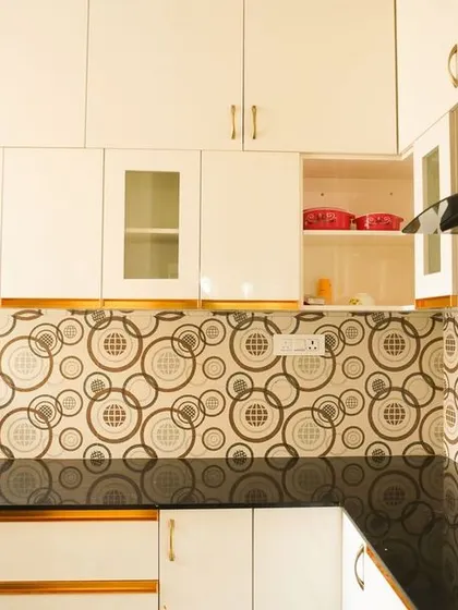 This angle shows the natural light from the window illuminating the patterned backsplash and white cabinets. The kitchen feels bright, spacious, and full of personality.