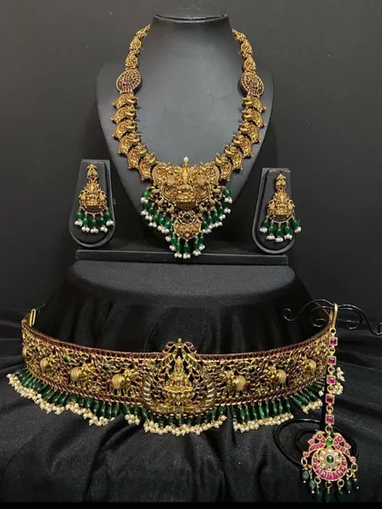 A closer look at the Nagas short necklace and vaddanam set. The green beads and pearls add a touch of elegance to the bold, antique design.