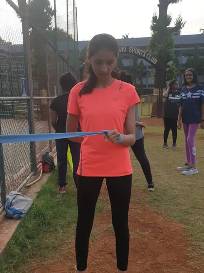 An athlete uses a blue theraband for an upper body strengthening exercise. Resistance bands are a versatile tool we use to build strength in the shoulders and back, which is important for maintaining proper running form.