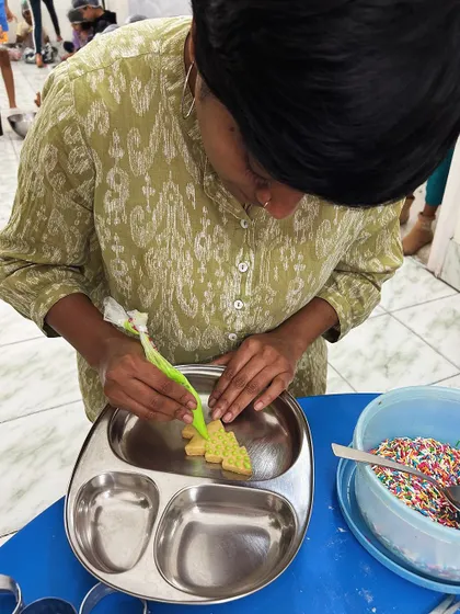 A parent volunteer guides children during a cookie decorating session at our Micro-School. These hands-on activities are a highlight for our learners.