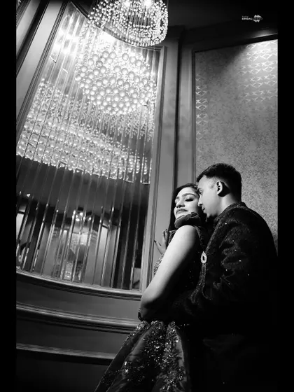 A dramatic black and white portrait under a stunning crystal chandelier. This low-angle shot creates a sense of intimacy and glamour.