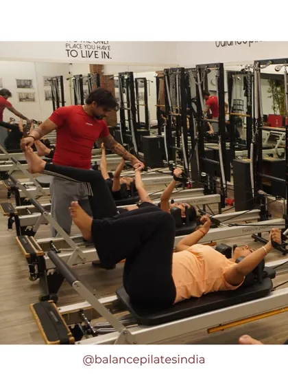 A trainer assists with leg work in straps, helping the client achieve a deeper stretch and better alignment.