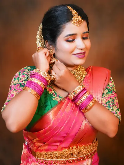 Getting ready for the big moment. Here, I'm helping the bride put on her antique jhumkas, the final touch to her beautiful reception look featuring a heavy, intricately designed choker and matching hip belt.