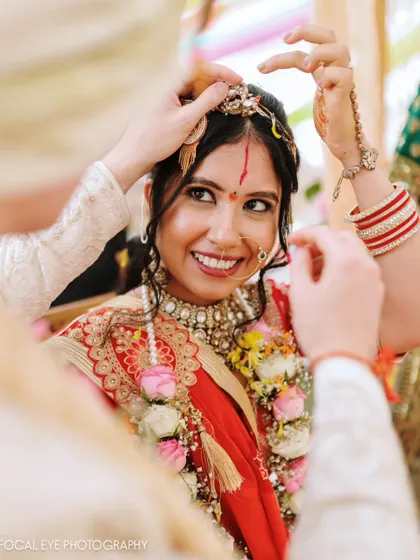 The groom helps the bride with her jewelry during the ceremony, a small, intimate gesture of care.
