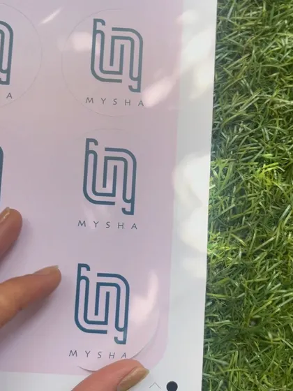 Holding up a sheet of the custom logo stickers for a client's packaging needs.