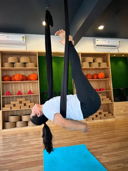 A student relaxes in a suspended cocoon-like pose, a deeply restorative and calming asana.