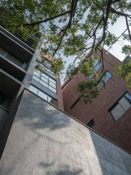 Close-up details of the ARCUS facade, highlighting the texture of the brickwork, the depth of the balconies, and how the structure was designed to accommodate existing trees.
