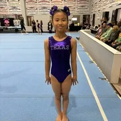 A Level 4 gymnast stands ready on the floor at the State Championships.