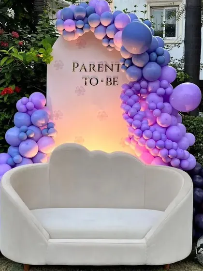 A 'Parents to Be' baby shower with a trendy purple color scheme. The modern sofa and disco balls add a fun and stylish touch.