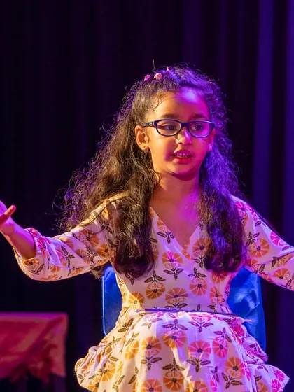 A performer seated, yet conveying strong emotion through facial expression and body language. Acting is about more than just standing and speaking.