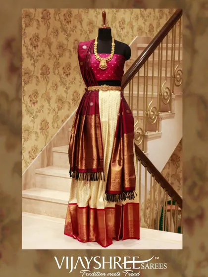A modern take on bridal wear, this Kanjivaram half saree in cream and maroon offers a stylish yet traditional option for pre-wedding functions.
