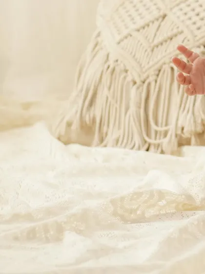 A detail-oriented shot focusing on a baby's hand and feet against a soft, lacey blanket, capturing the tiny features of his first year.