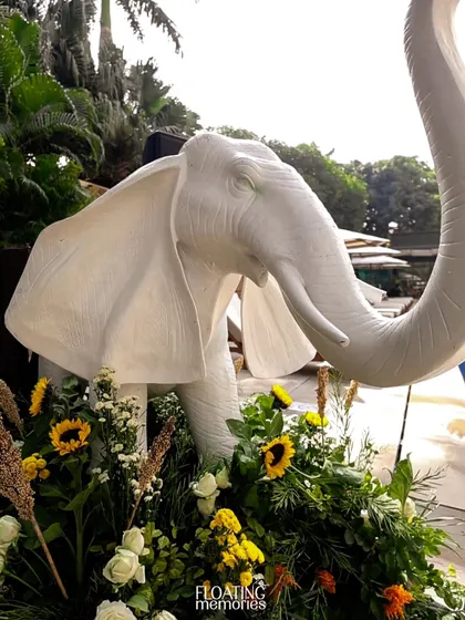 A majestic white elephant prop stands among sunflowers and lush greenery, adding a touch of gentle grandeur to the safari theme.