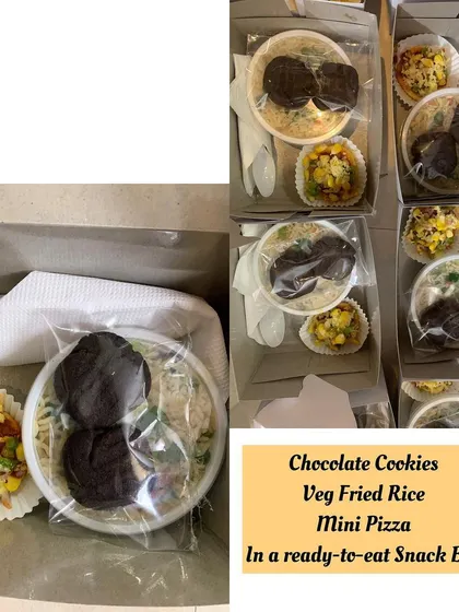 A ready-to-eat snack box containing chocolate cookies, veg fried rice, and mini pizza.