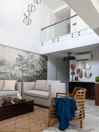 In this Jaipur penthouse, we used a custom wallpaper inspired by the forests of Ranthambore to create a dramatic feature wall. This design choice brings a piece of Rajasthan's natural heritage into a modern, double-height living space.
