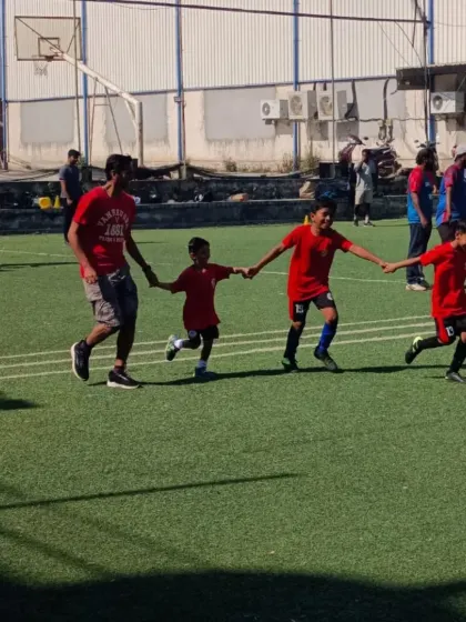 A beautiful moment of teamwork as a father and his children hold hands while dribbling a ball.