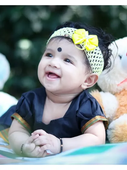 An adorable close-up from an outdoor baby milestone session. We can include different outfits, like this beautiful traditional dress, and props like teddy bears to add personality to the photos.