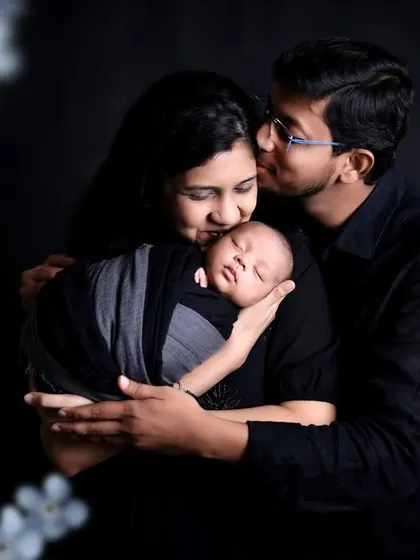 A tender family moment as both parents embrace their newborn. The floral overlay adds a soft, artistic touch to this beautiful family portrait.