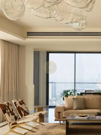 We incorporated unique textures like these cowhide-print chairs to add a touch of unexpected character to the otherwise serene and neutral living room. The large glass chandelier continues to be a focal point, tying the entire space together.