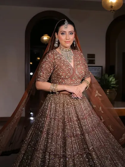 A full-length shot of the bride, her lehenga flowing around her. The jewellery adds a touch of sparkle to the grand setting.