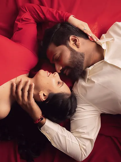 An artistic, top-down shot capturing an intimate gaze between the couple. The rich red fabric creates a beautiful canvas of love.