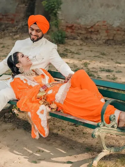 A playful and romantic shot of the couple relaxing on a park bench. This shows the fun and comfortable side of their relationship.
