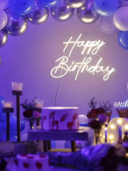 A close-up of the 'Happy Birthday' neon sign against a backdrop of blue and silver balloons in our 'Smokey Lounge' setup.