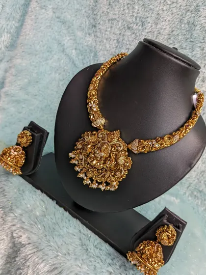 This unique Kadga-style necklace with a large Lakshmi pendant adds a touch of royalty to any traditional outfit. It's perfect for making a bold statement.