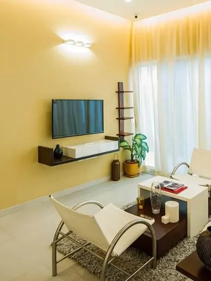 A view from a bright, yellow-toned living area into a bedroom with a contrasting dark and moody theme. This juxtaposition of color and light defines the transition from a public to a private zone within the apartment.