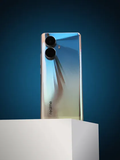 A commercial product shot of the realme 10 Pro+ 5G on a white block against a blue background, emphasizing its sleek design.