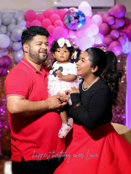 A candid family moment at a birthday party, with the parents looking lovingly at their daughter.