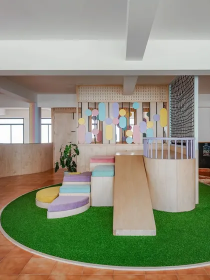 The indoor play area, with its slide and climbing steps, is a hub of joyful activity and physical development.