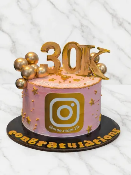 A special cake to celebrate a 30K Instagram milestone. The pink and gold design features the Instagram logo and is topped with golden chocolate spheres.
