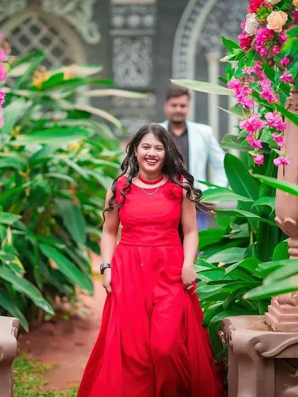 A joyful, candid shot of the bride-to-be walking through a garden path, with her partner following behind.