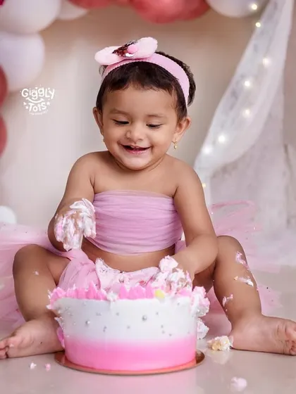 This little girl is having a blast digging into her pink ombre cake during her butterfly-themed cake smash.