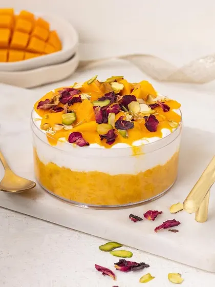 A mango tub dessert garnished with rose petals and pistachios, giving it a fusion Indian twist.