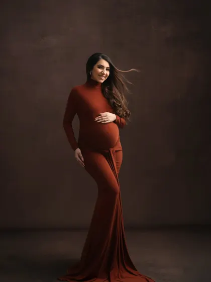 My studio can transform to match any mood. Here, a rich, earthy-toned gown and a darker, textured backdrop create a fine-art portrait that feels both powerful and intimate, focusing on the beautiful silhouette of pregnancy.