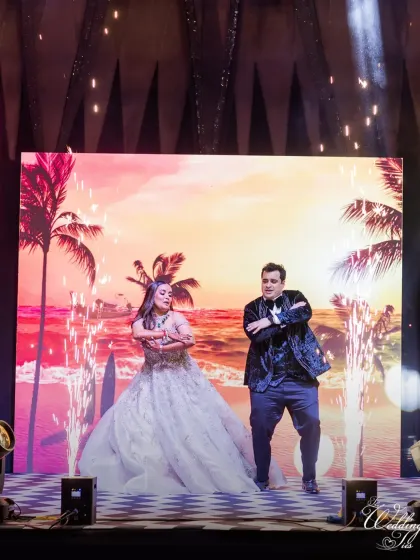 The couple brings a fun, beachy vibe to their Sangeet performance with a tropical sunset backdrop on the LED screen.