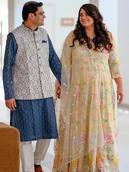 A wider shot that captures more of the environment, showing the couple walking together in a bright, airy hallway during their maternity session.