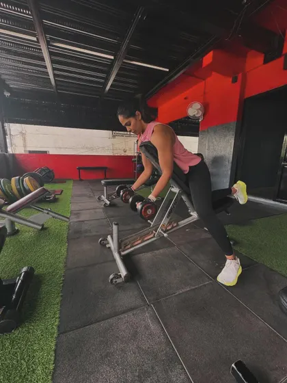 A client performs a single-arm dumbbell row on a bench, isolating the back muscles to build strength and improve posture.