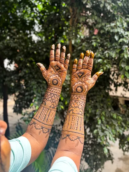 The fresh application of a bridal mehendi, held up against a natural background, ready to transform into a beautiful dark stain.