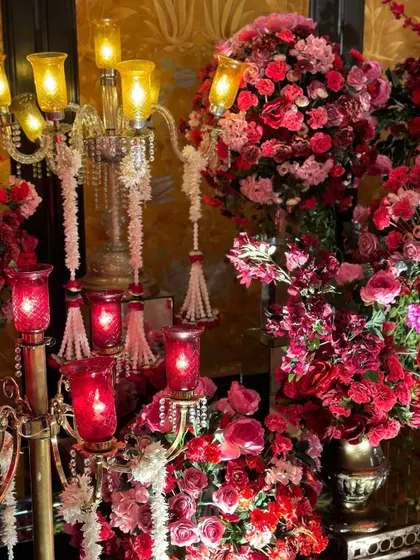 A close-up of a magnificent floral arrangement featuring red roses and other blooms, set beside an ornate crystal candelabra, showcasing pure opulence.