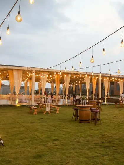 An inviting setup for a relaxed Mehendi evening. We used rustic wooden benches and tables, complemented by soft drapes and warm lighting, to create a comfortable and stylish space for guests to mingle.