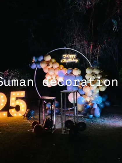 An outdoor 25th birthday party at night. The minimalist decor features a balloon garland on a ring frame and large '25' marquee numbers.